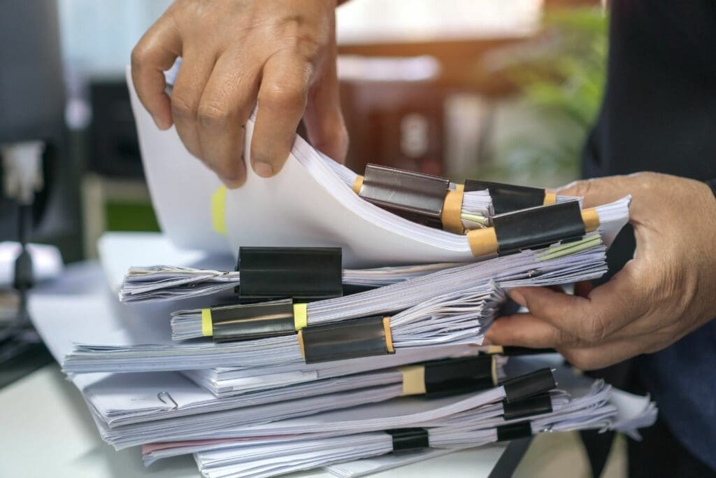 a bodyshop manager sorts through a stack of paperwork thanks to excessive admin generated by his legacy management system