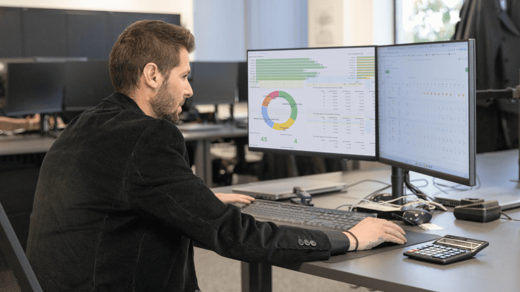 A bodyshop manager sitting in the office of a repair shop, tracking live business performance data and employee productivity insights through the intuitive bodyshop management system, Onyx BMS.